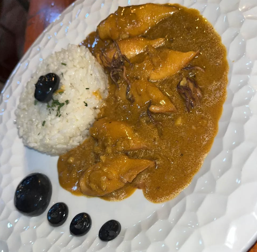 Un plato de comida con arroz y aceitunas encima.