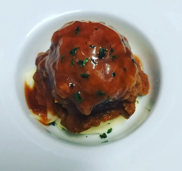 Un plato blanco cubierto con albóndigas y salsa.