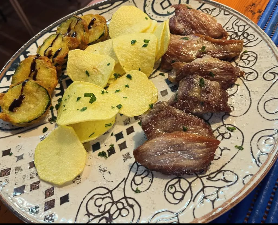 Un plato de comida con carne y patatas fritas encima.