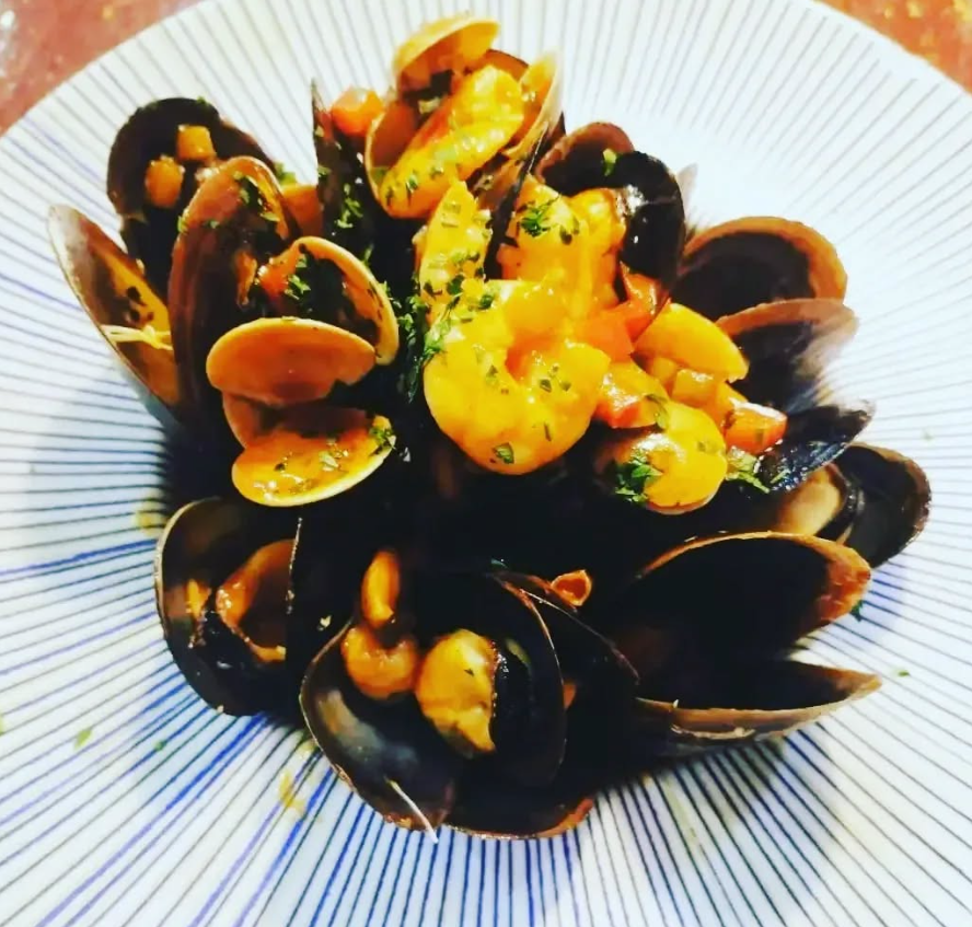 Un plato azul y blanco cubierto con almejas y camarones.