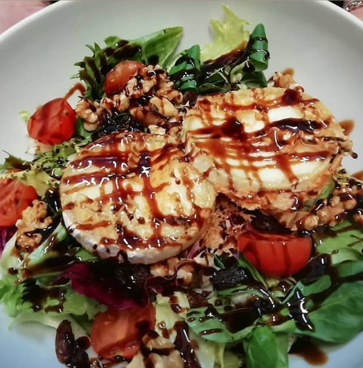 Un tazón blanco lleno de ensalada de verduras y queso.