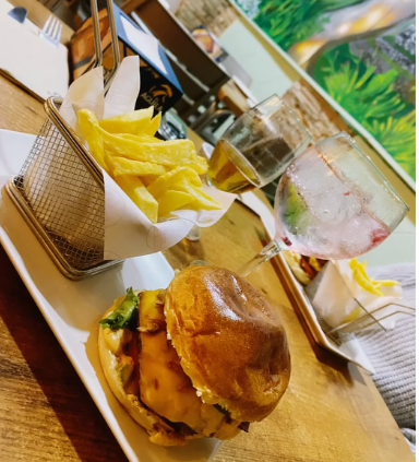 Una hamburguesa y papas fritas están en un plato sobre una mesa.