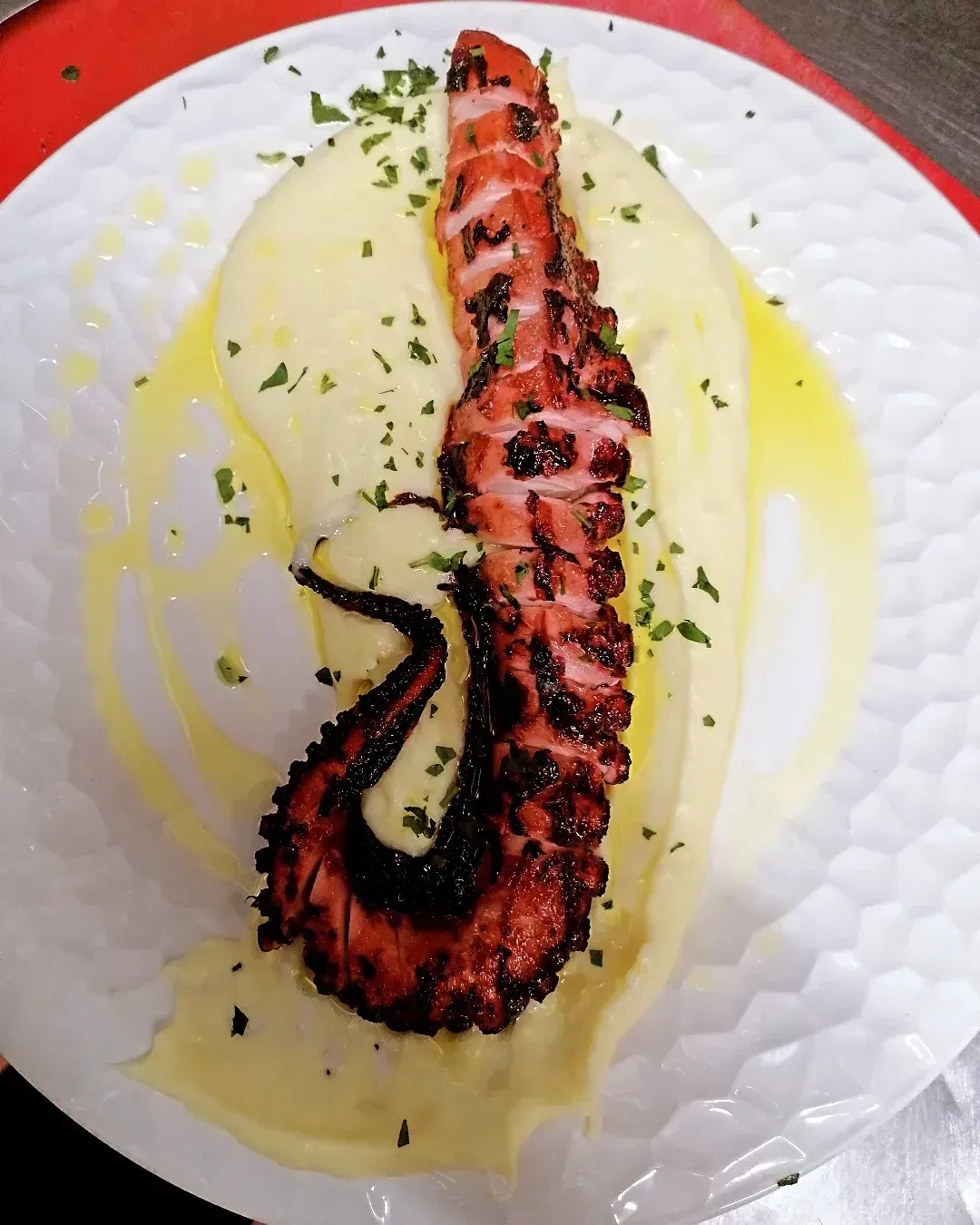 Un plato de comida con un pulpo encima de puré de patatas.