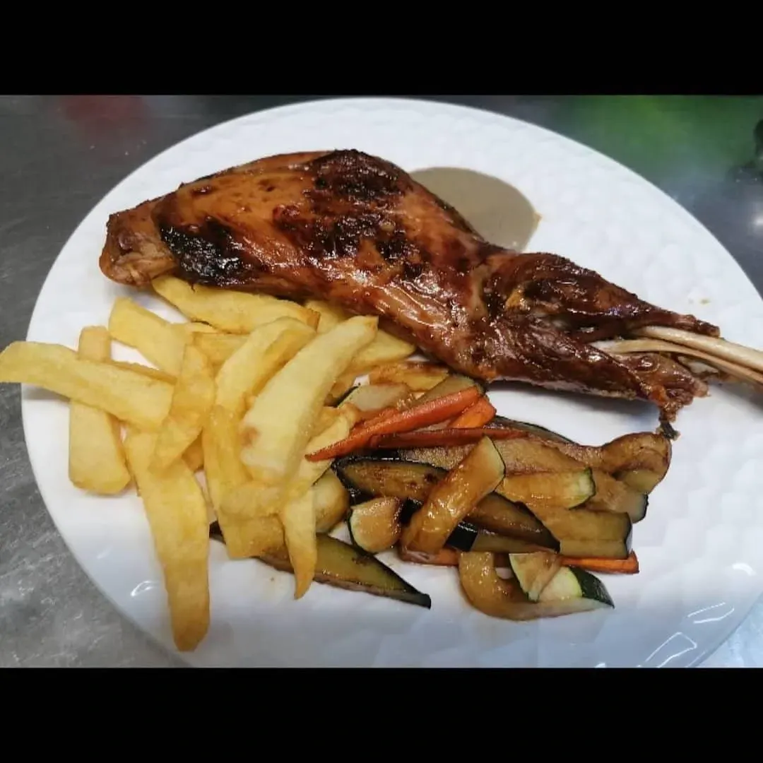 Un plato blanco cubierto con carne y papas fritas.