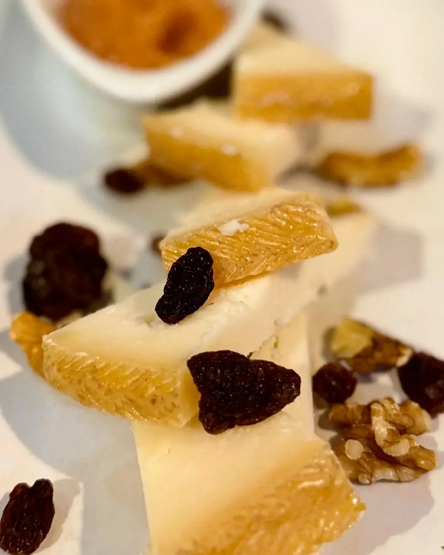 Un plato blanco cubierto con rodajas de queso, pasas y nueces.