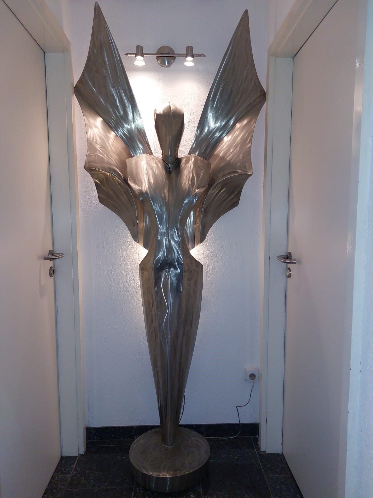 Menschengroße Metallfigur in einem Flur, beleuchtet