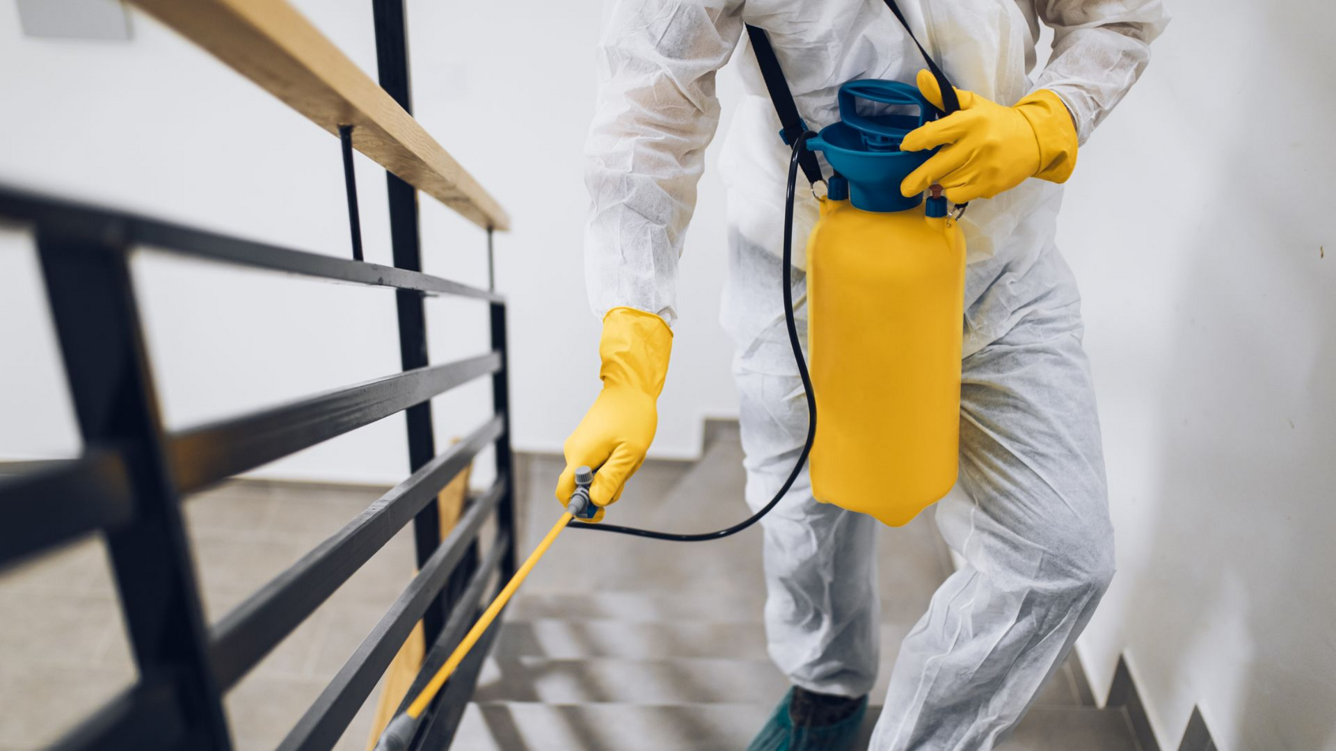 Une personne en combinaison de protection pulvérise un produit.