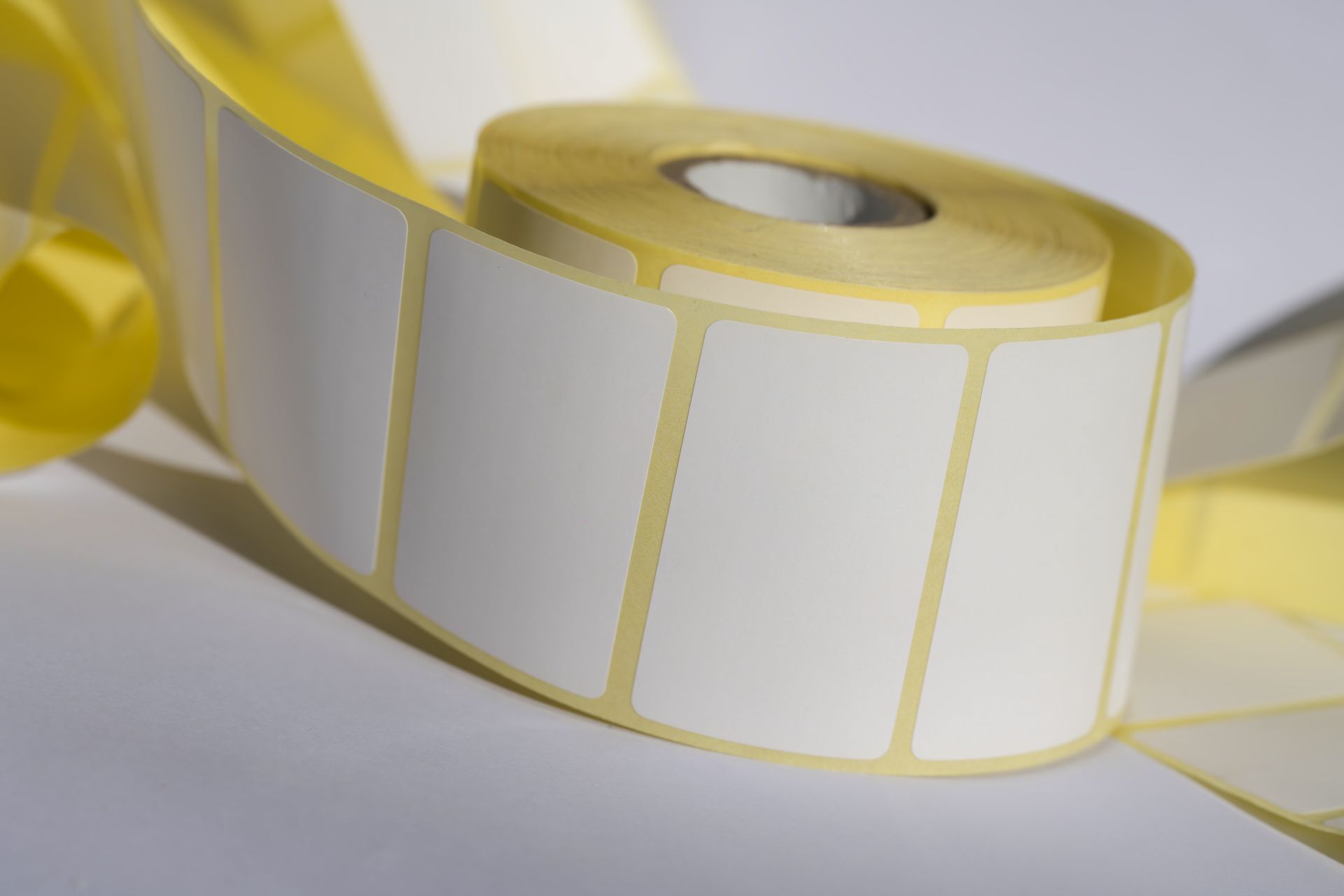 Eine Rolle mit weißen Etiketten liegt auf einer weißen Fläche.