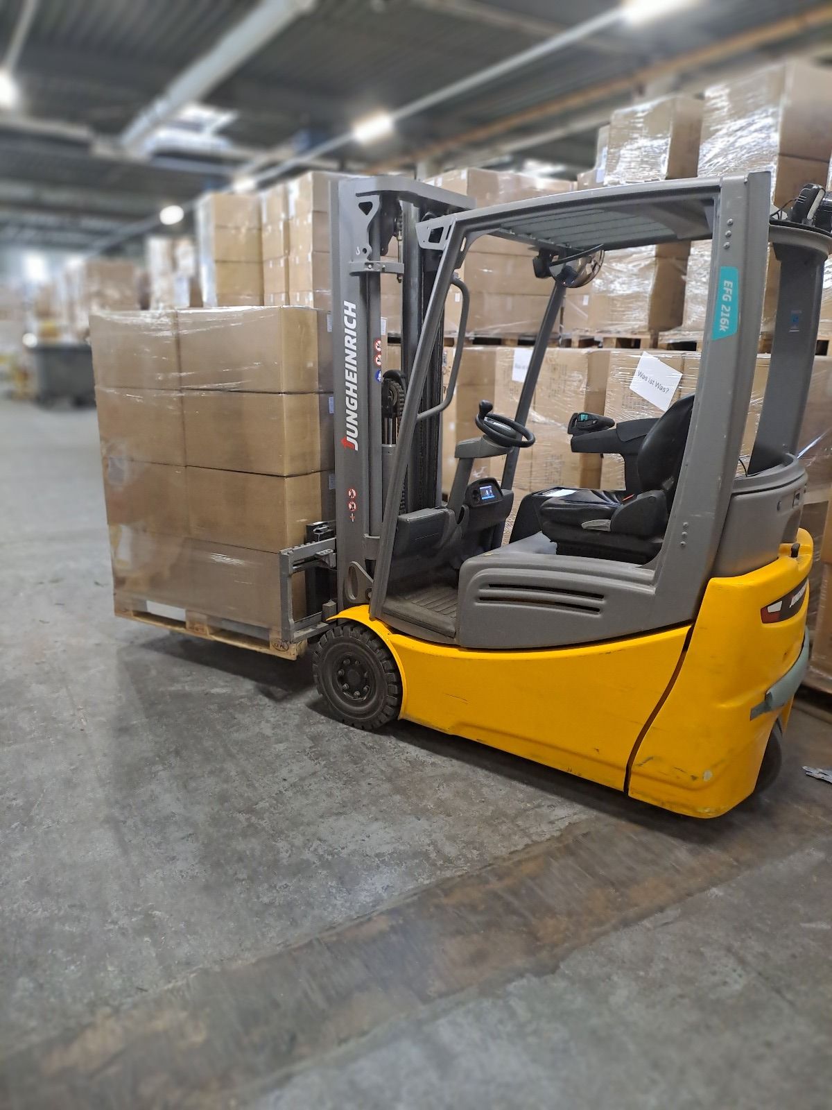 Ein gelber Gabelstapler bewegt eine Palette mit Kisten in einem Lagerhaus.