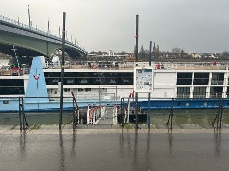 Ein Boot liegt im Wasser neben einer Brücke.