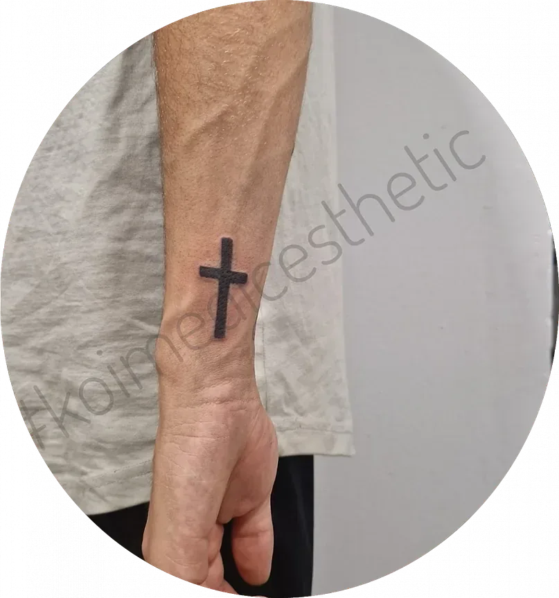 Un hombre tiene un tatuaje de una cruz en su muñeca.