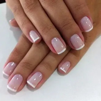 Un primer plano de las uñas de una mujer con manicura francesa.