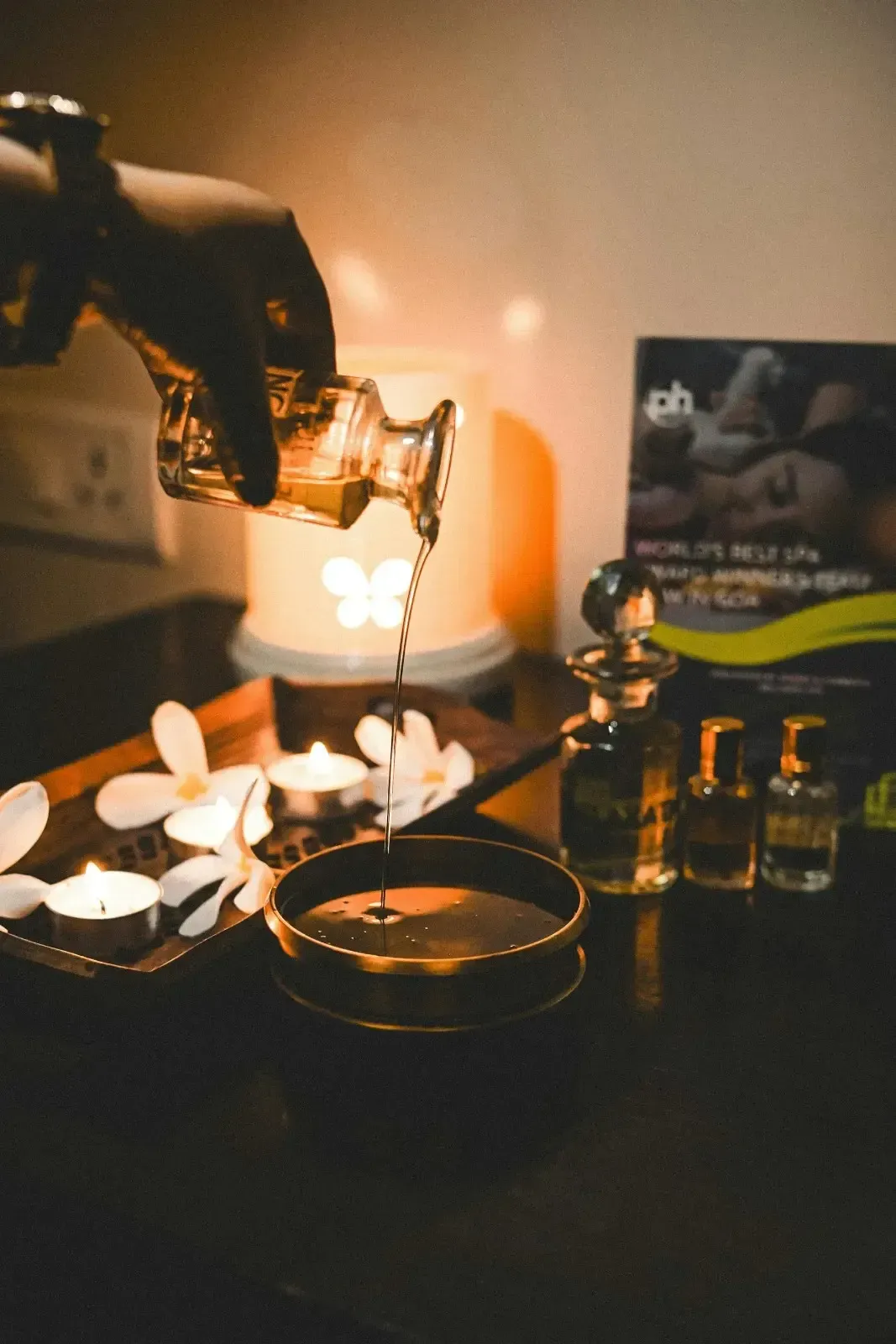 Ambiente de café con iluminación tenue, con una bebida vertiéndose, tazas y botellas de vidrio sobre una mesa.