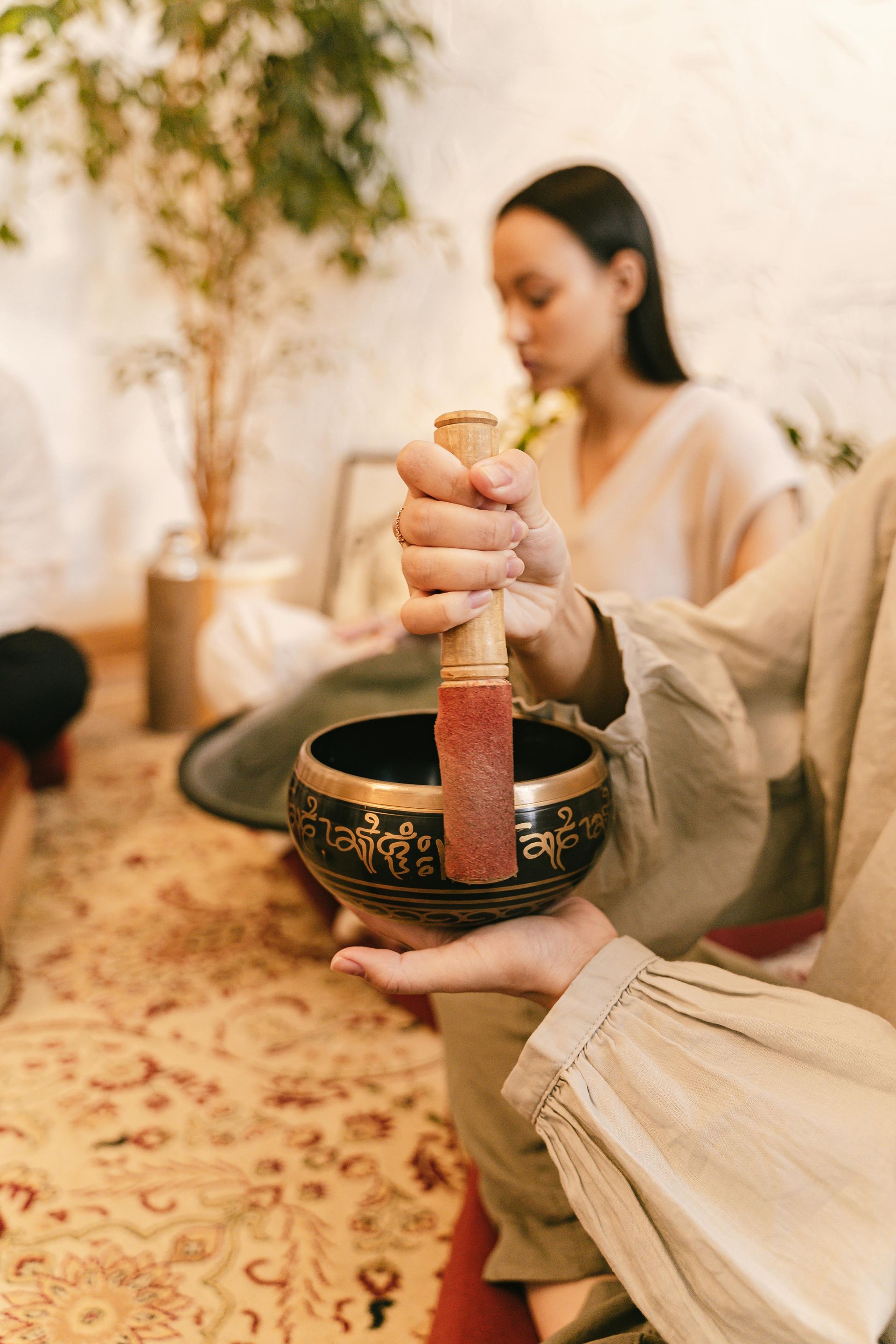 Manos tocando un cuenco tibetano durante una tranquila sesión de meditación en interiores.