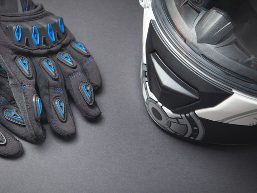 Gant blindé noir et bleu à côté d'un casque de moto noir sur une surface grise