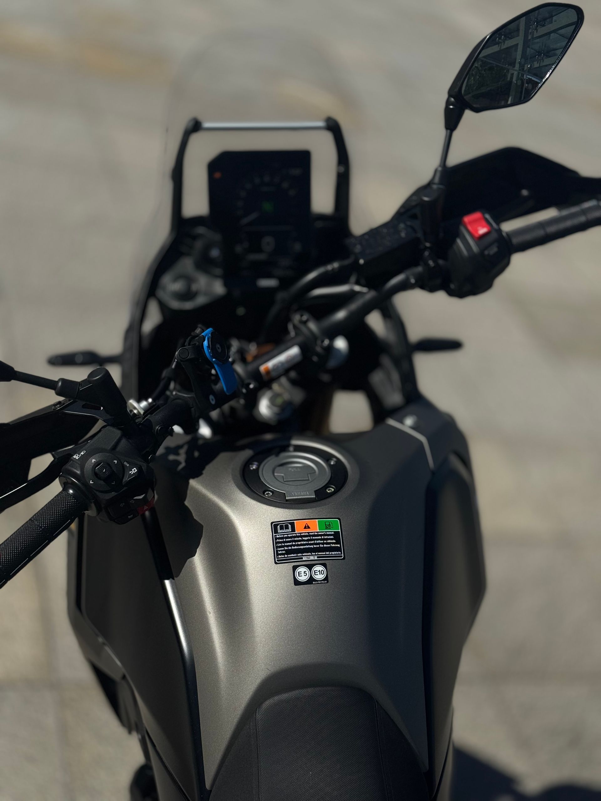 Moto sport-touring noire garée à l'extérieur, avec pare-brise et sacoches latérales