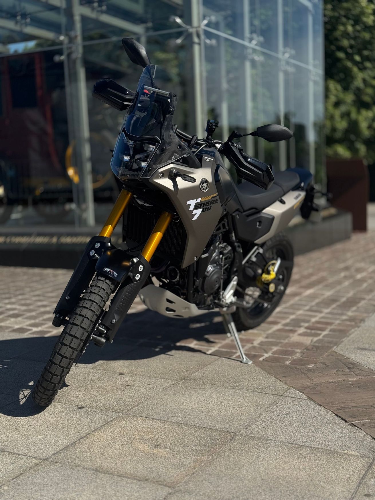 Trois motos garées de nuit devant une vitrine illuminée et recouverte de graffitis.