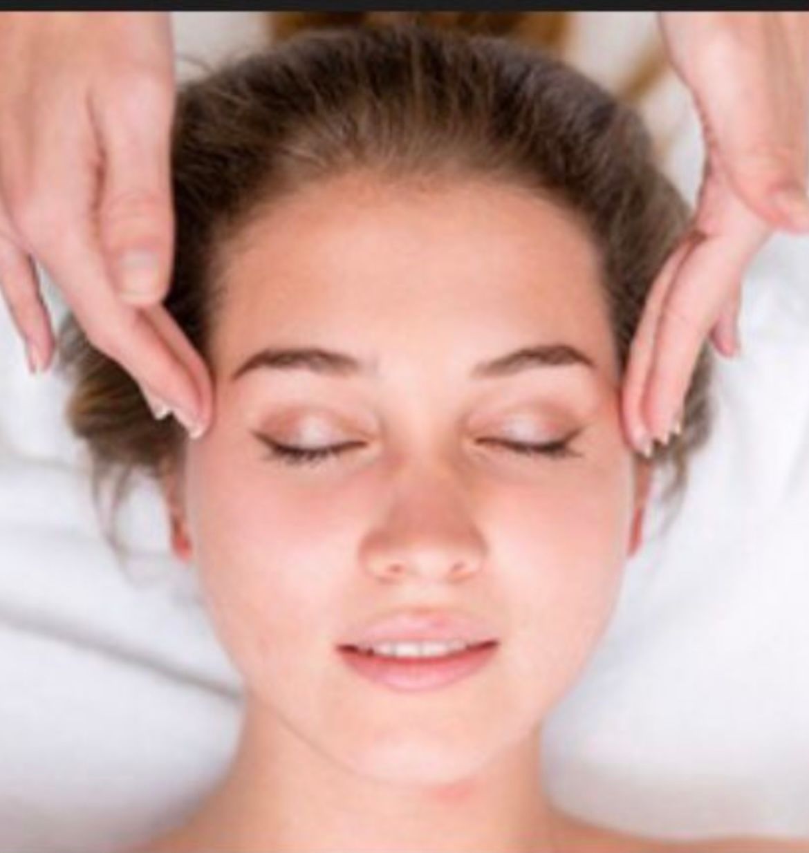 Des pieds vernis en noir, effleurés par une main tenant une fleur, probablement dans un salon de beauté.