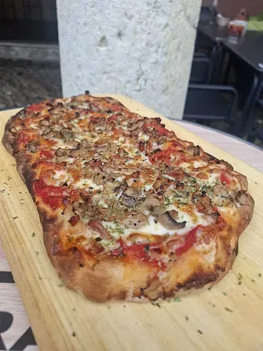 Una pizza está colocada sobre una tabla de cortar de madera.