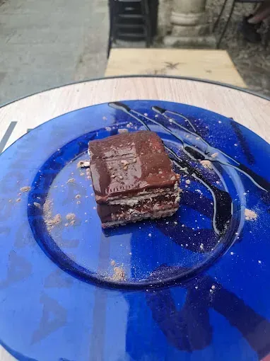 Un trozo de pastel de chocolate está en un plato azul sobre una mesa.