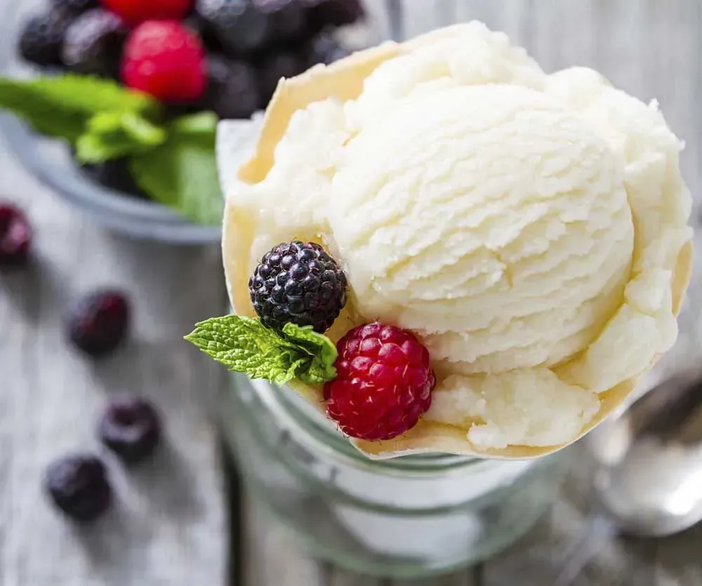 Una bola de helado con bayas encima en un vaso.