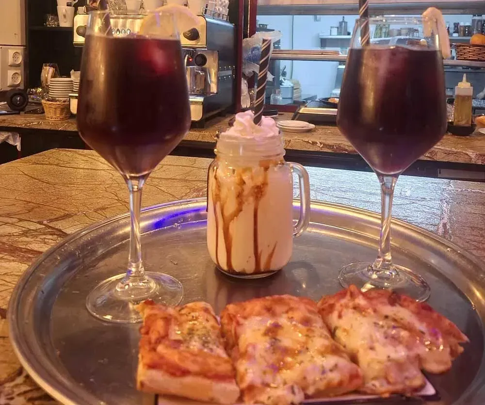 Dos copas de vino y una porción de pizza en una bandeja.