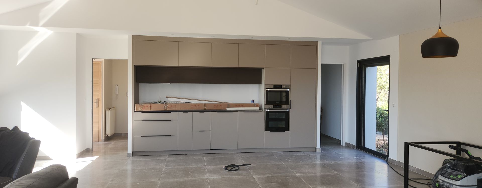 Ouverture d'une cuisine lumineuse blanche et beige et le revêtement au sol c'est un carrelage