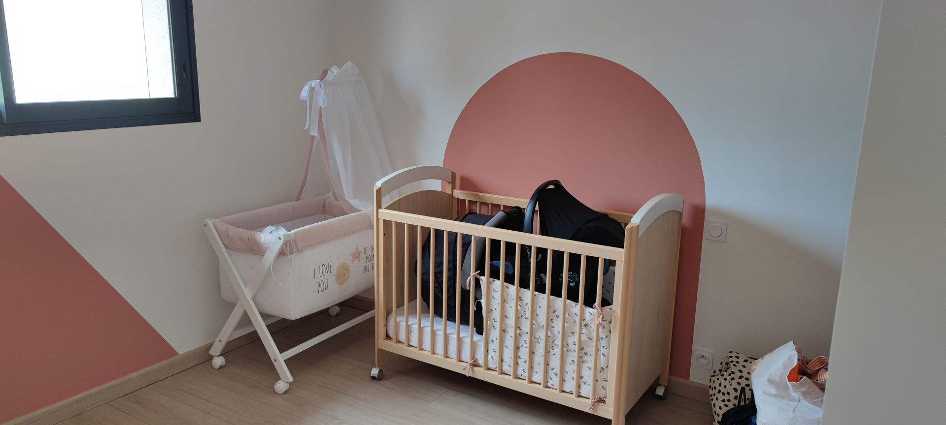 Chambre blanche et rose avec deux berceaux.