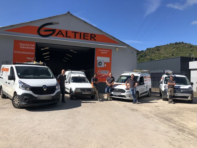 Un groupe de personnes avec des camionnettes aux couleurs de la marque se trouve devant un bâtiment portant l'inscription « Galtier ».