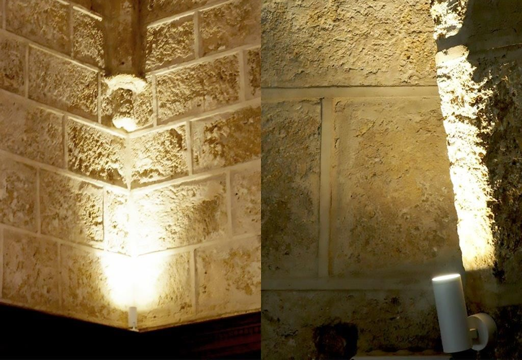 Deux sections d'un mur en pierre éclairées par des projecteurs.