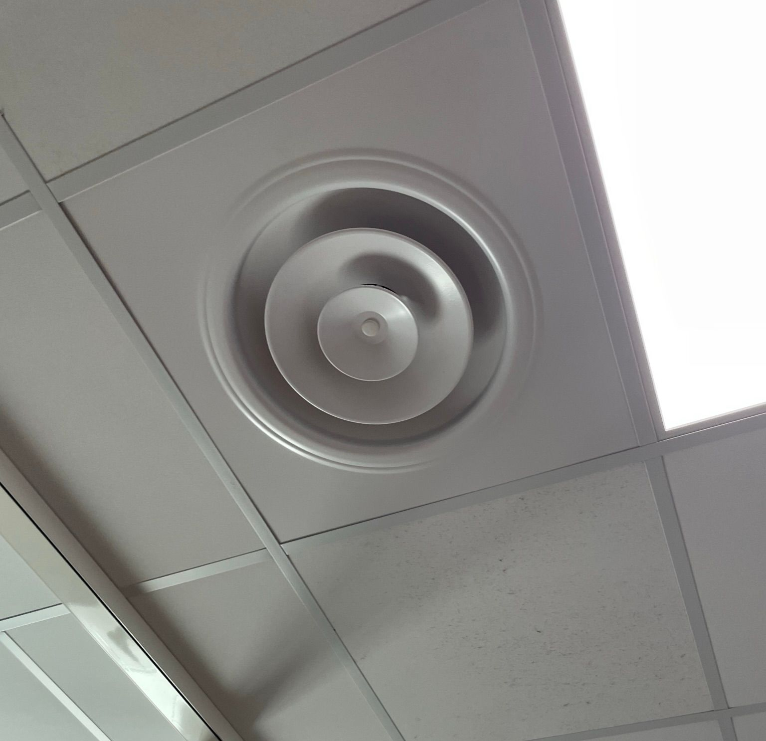 Plafond avec grille d'aération circulaire.