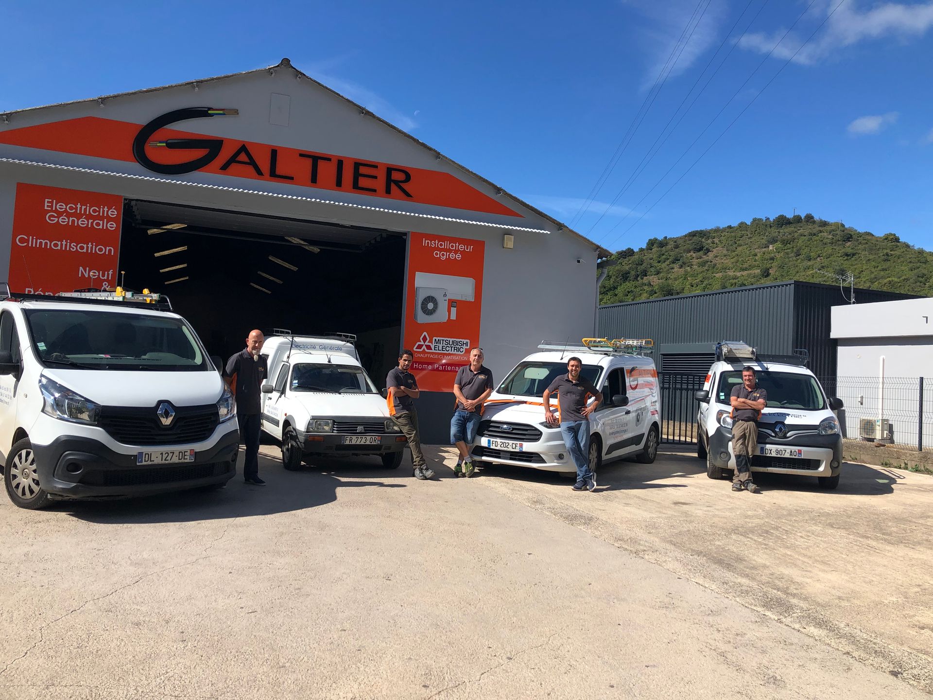 Un groupe de personnes avec des fourgonnettes de service devant un bâtiment.