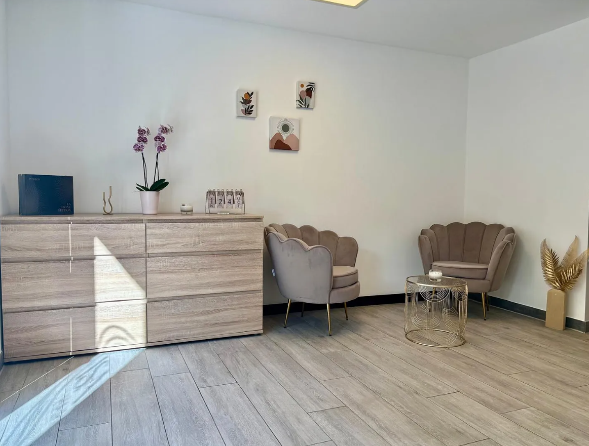 Espace d'accueil avec mobilier en bois clair, chaises roses et petites œuvres d'art.
