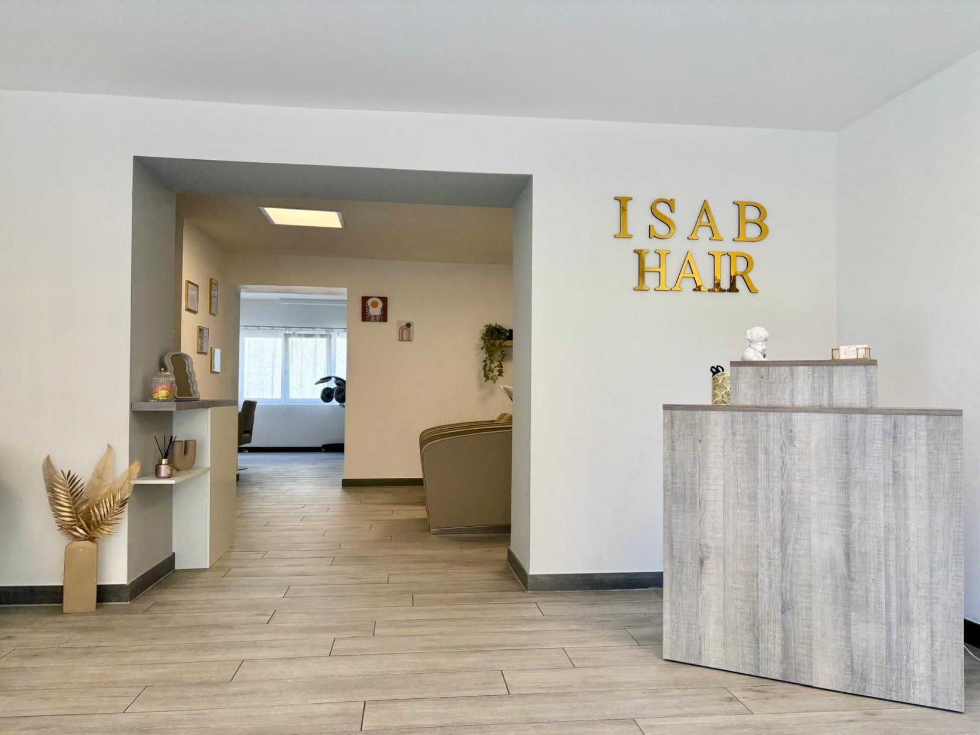 Intérieur d'un salon de coiffure avec un comptoir d'accueil et une enseigne « ISAB HAIR ».