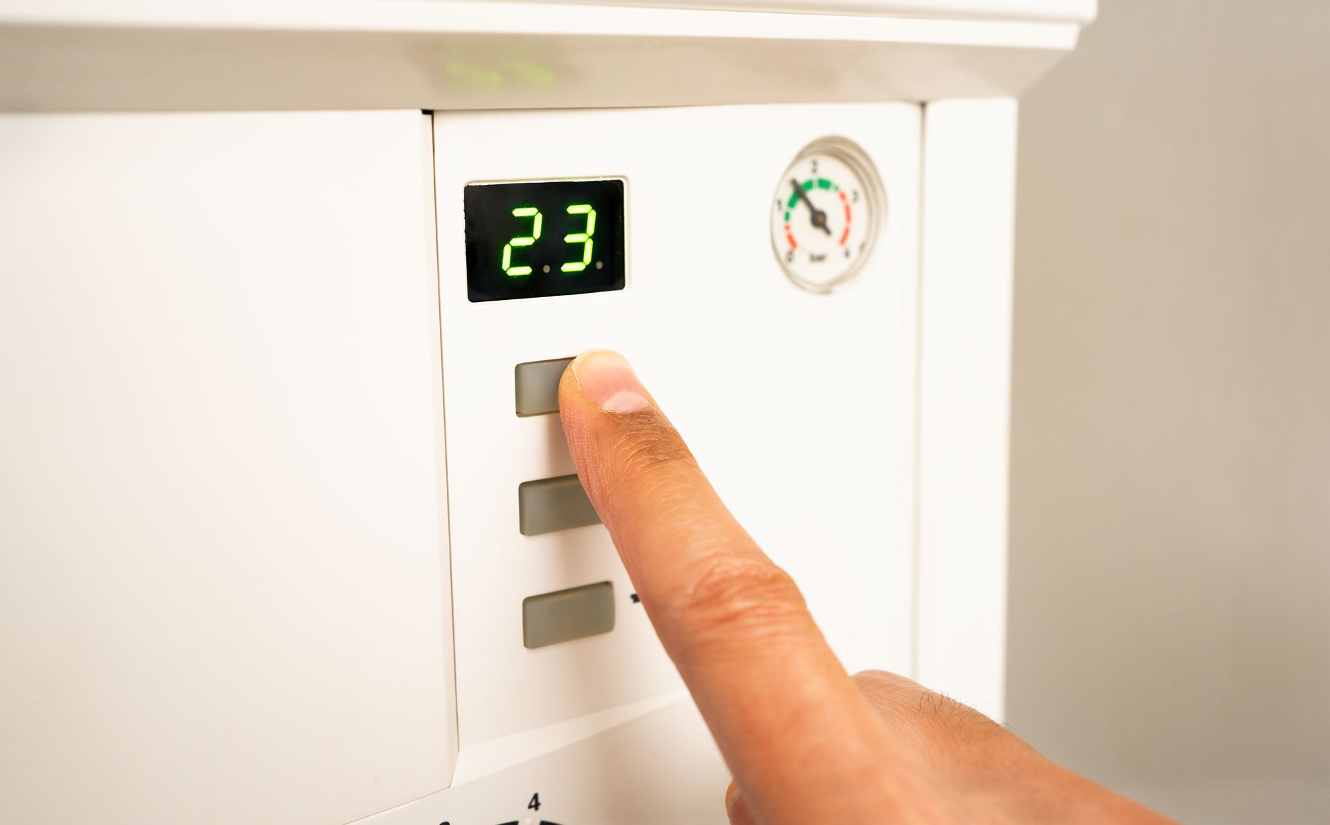 Doigt appuyant sur un bouton de chaudière noté à 23°