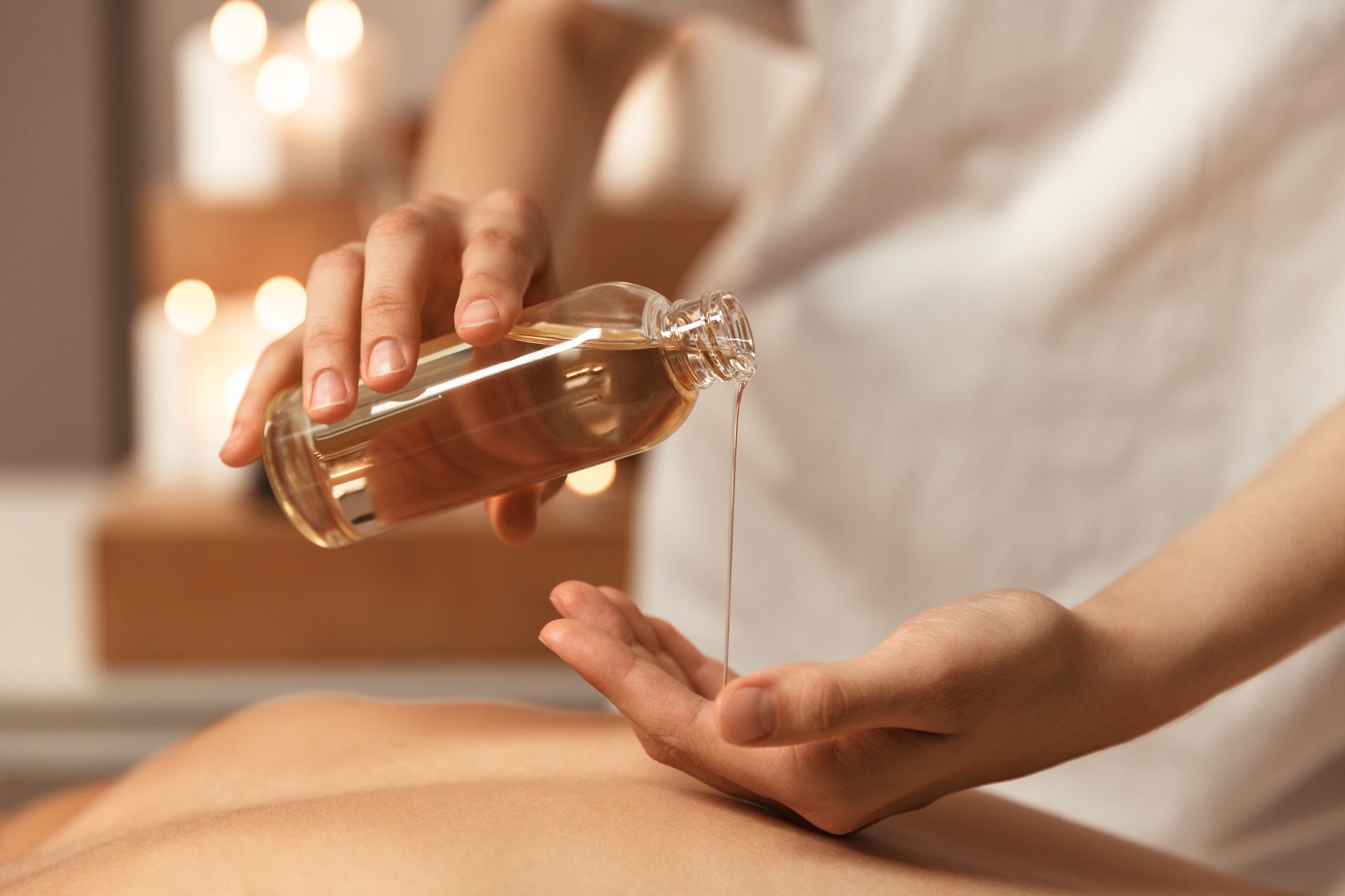 Des mains versent de l'huile dans une paume ouverte lors d'un massage au spa.