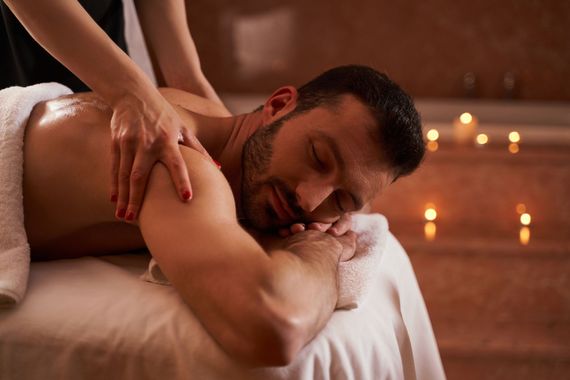 Une personne recevant un massage du dos dans une salle de spa éclairée aux chandelles.