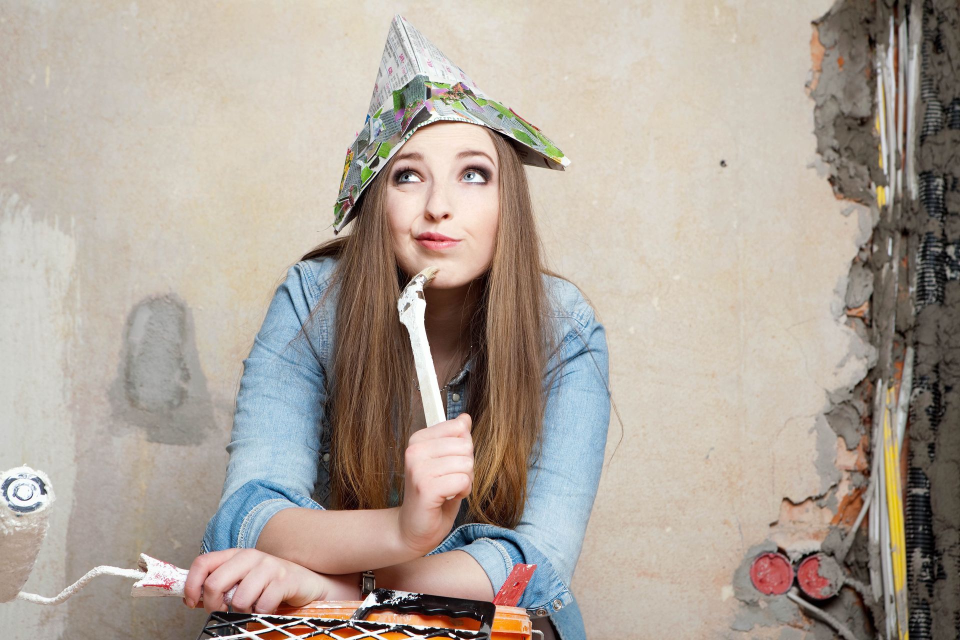 Frau mi Papierhut auf dem Kopf und Pinsel in der Hand