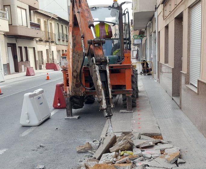 Un hombre conduce un tractor en una calle de la ciudad.