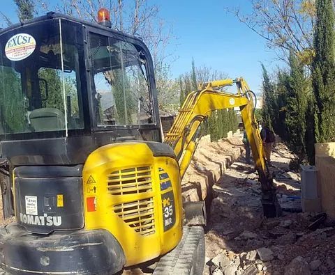 Una excavadora Komatsu amarilla y negra está cavando en la tierra.