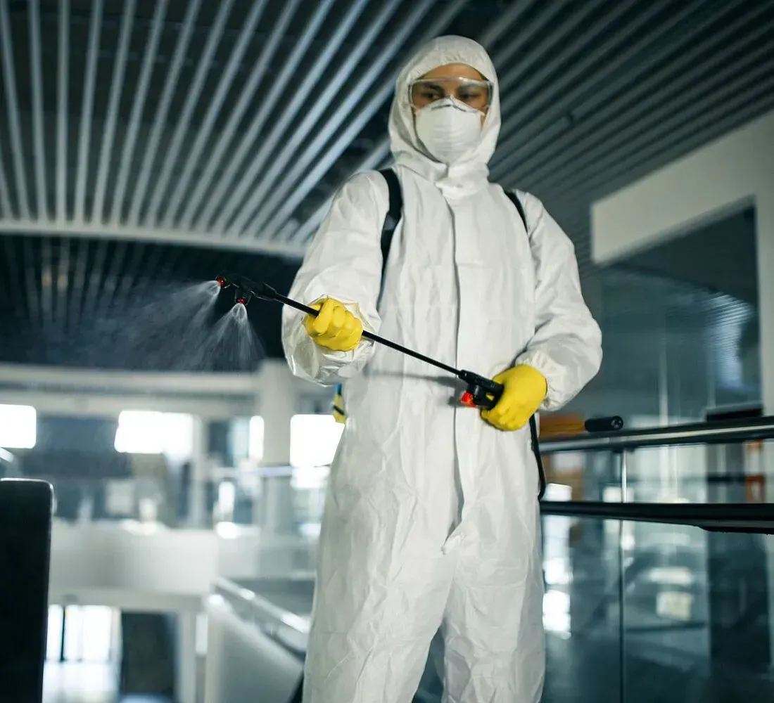 Un hombre con un traje de protección está rociando una habitación con un pulverizador.