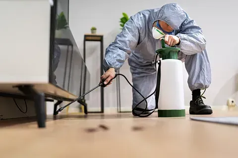 Un hombre con un traje de protección está rociando una habitación con un pulverizador.