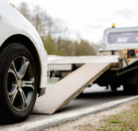 Une voiture blanche est remorquée par une dépanneuse.