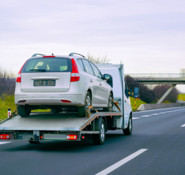 Une voiture est remorquée par une dépanneuse sur une autoroute.