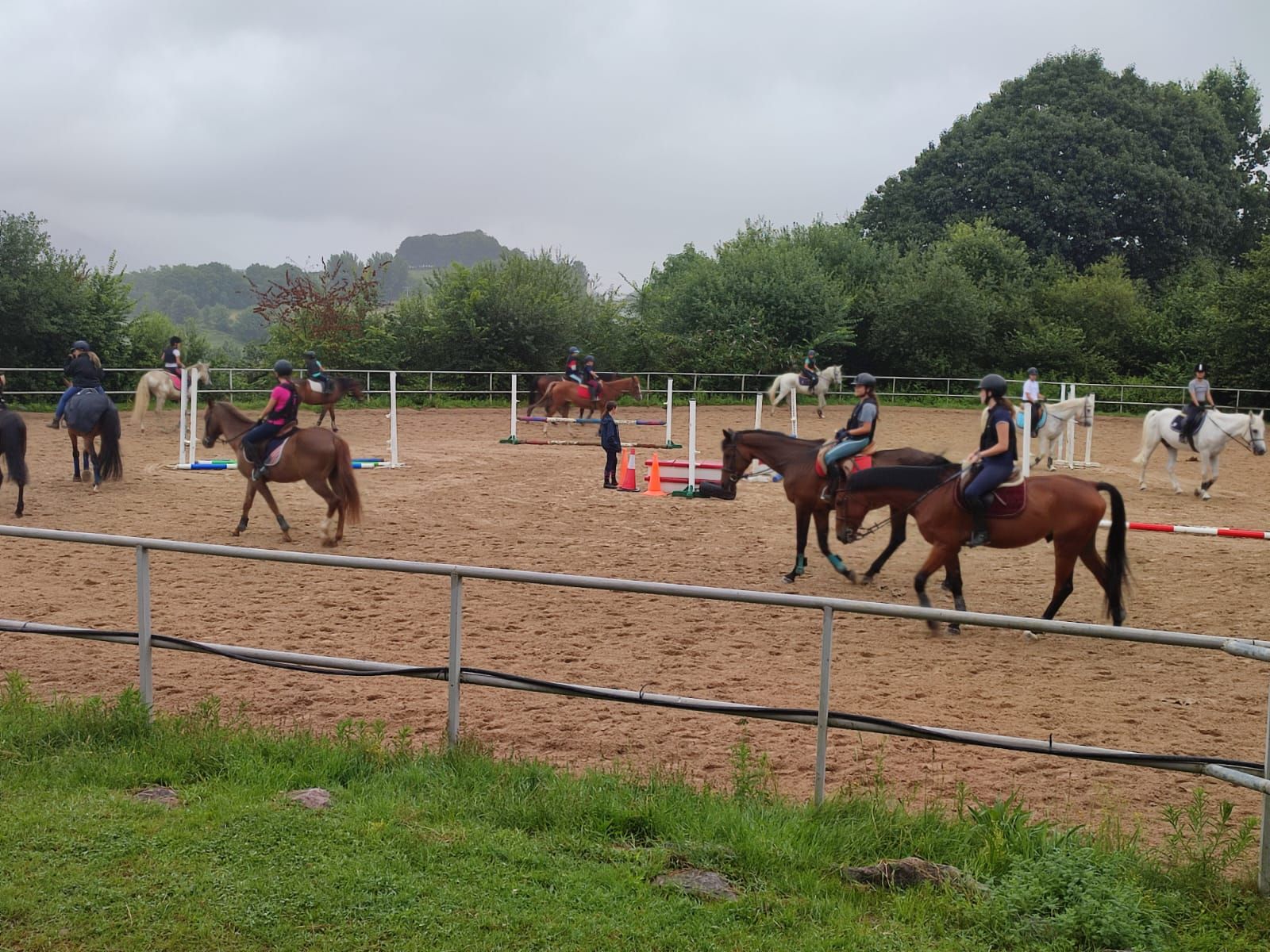 Un grupo de personas montan a caballo en una arena de tierra.