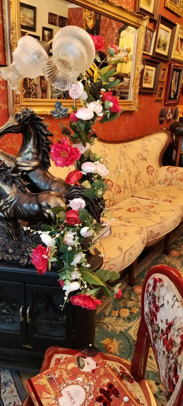 Interior ornamentado con arreglos florales, estatua y muebles antiguos.