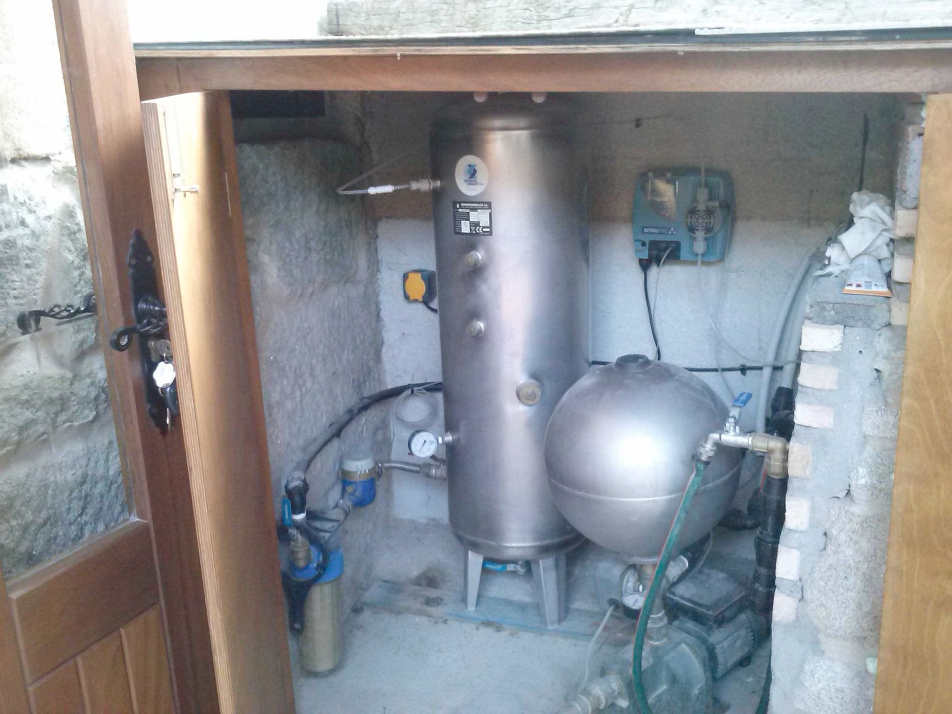 Cuarto de calderas compacto con depósito de agua caliente, vaso de expansión, tuberías y panel de control en un armario de servicio