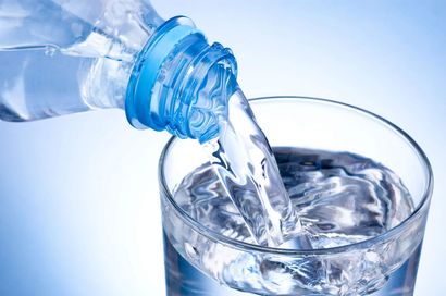 Agua vertiéndose de una botella de plástico en un vaso transparente