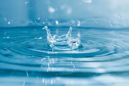 Salpicadura de agua que crea ondas en una superficie azul tranquila