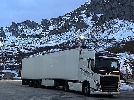 Un camión blanco está estacionado frente a una montaña nevada.